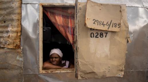 Bonisiwe looks out the window of the one-room shack she shares with three of her sons in Mamelodi township near Pretoria, South Africa. 